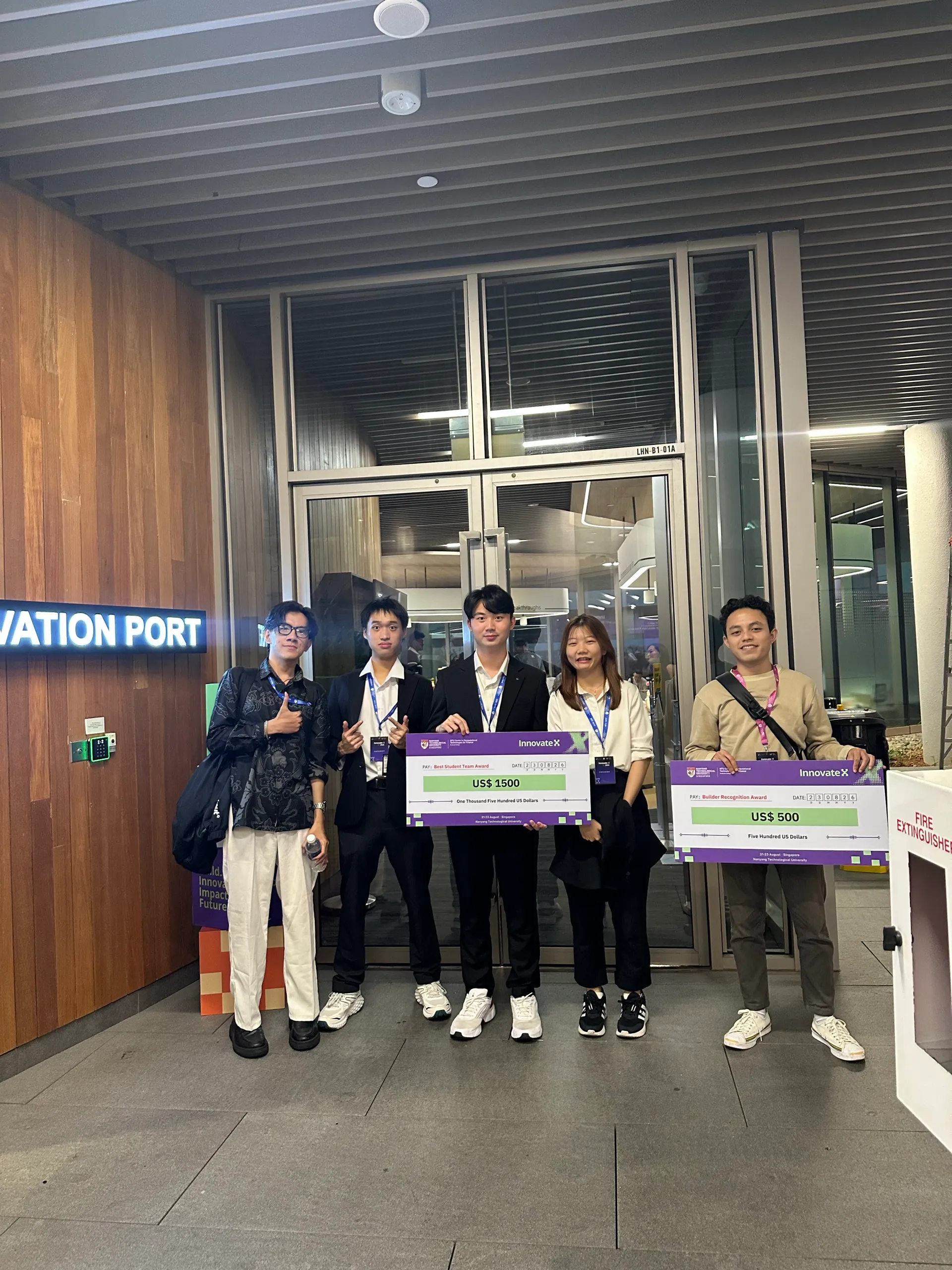 Us with PayMaster, the Malaysian team that won Best Student, holding the cheques at the Innovation Port entrance