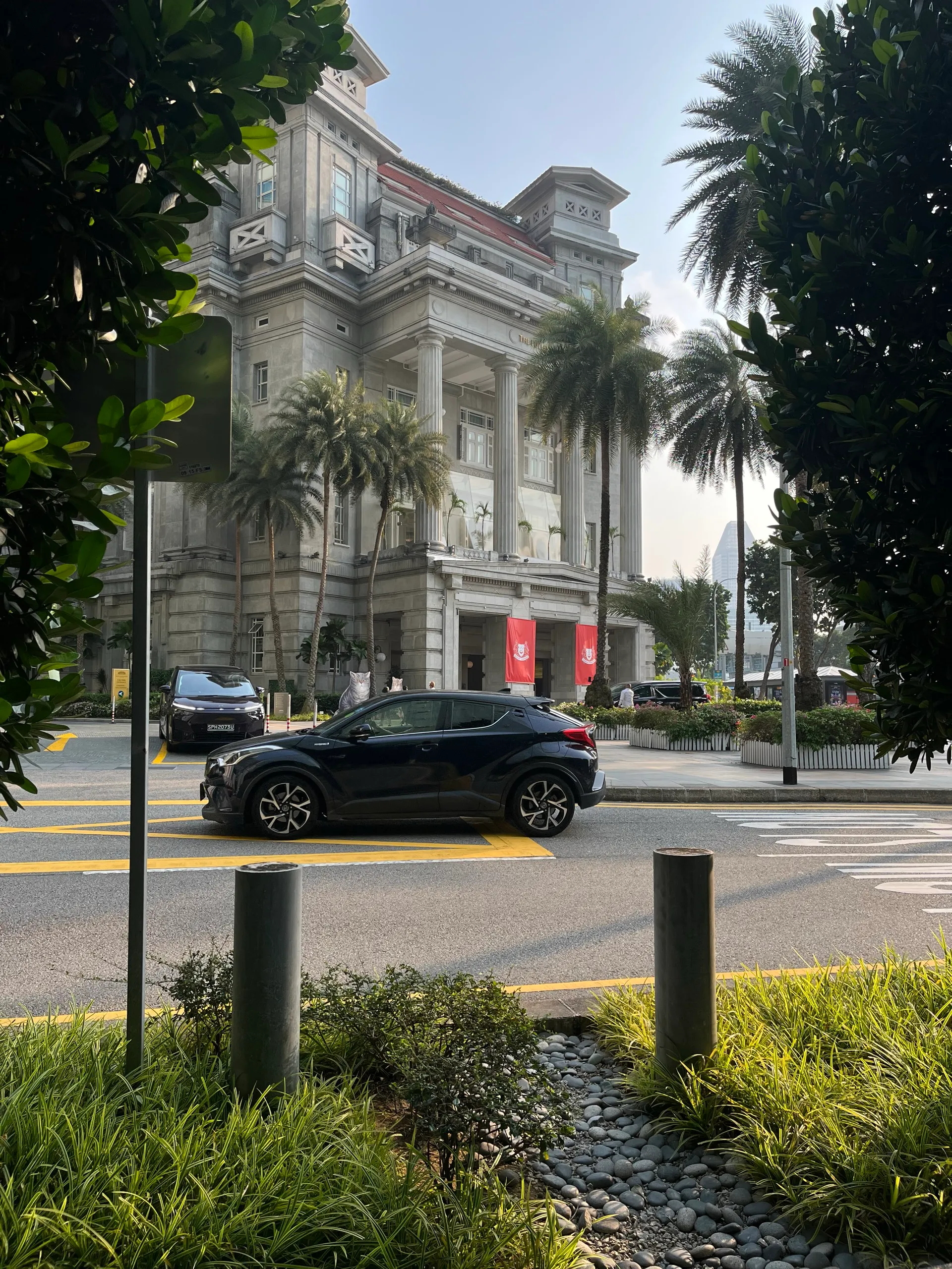 The Fullerton Hotel behind the trees on the walk to the Merlion