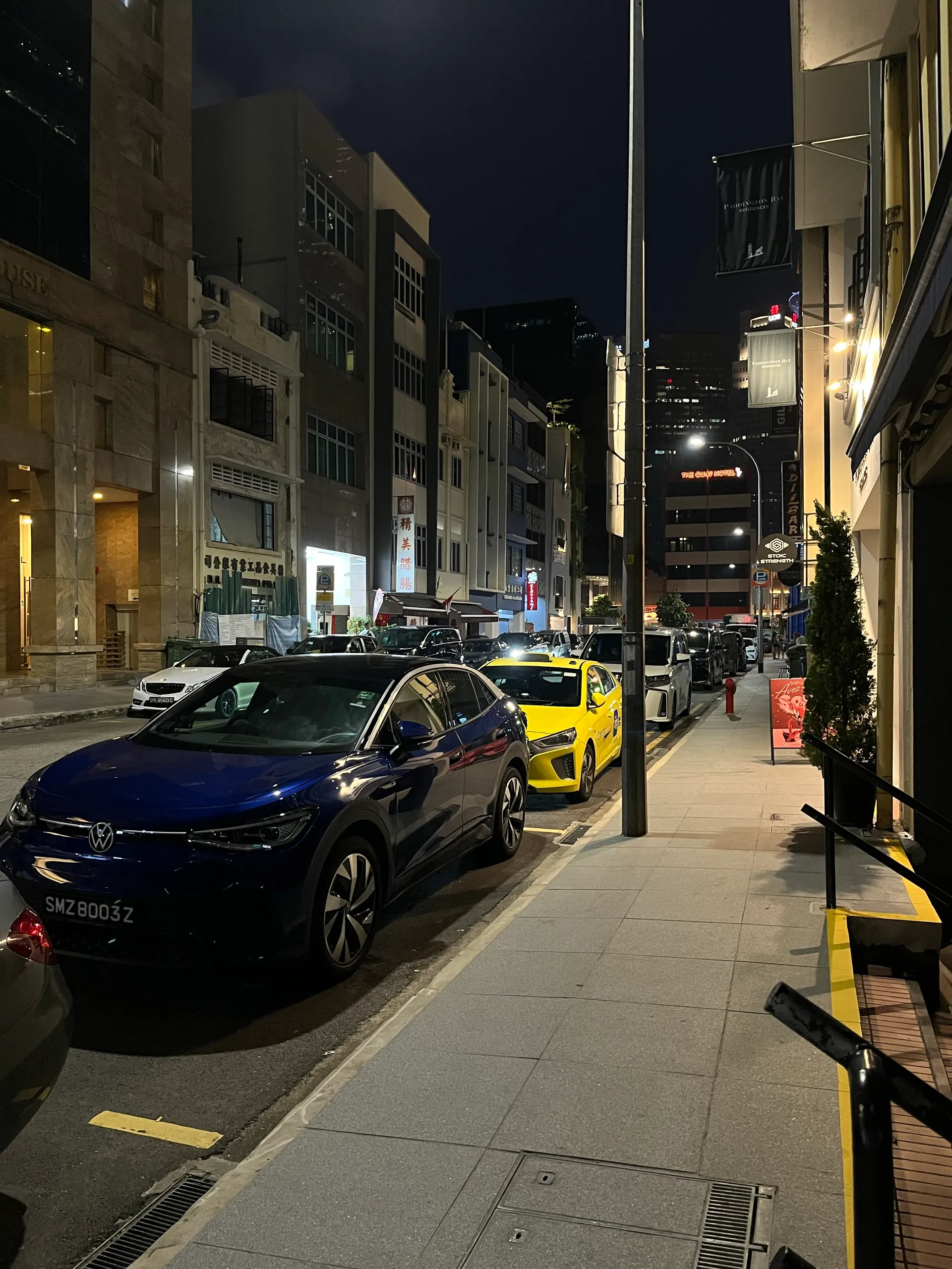 Parked cars and lit shopfronts on the night walk back