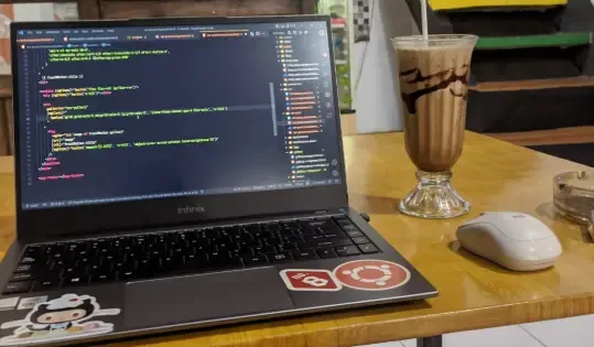 Rizki's laptop cafe setup with an iced coffee